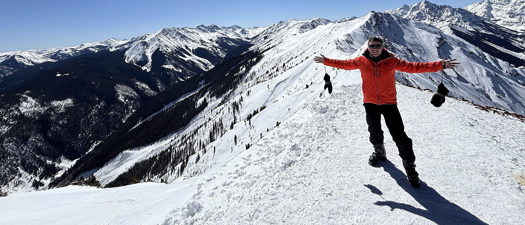 Bryen Alperin on the Highland Bowl ridge above Aspen with the Maroon Bells behind
